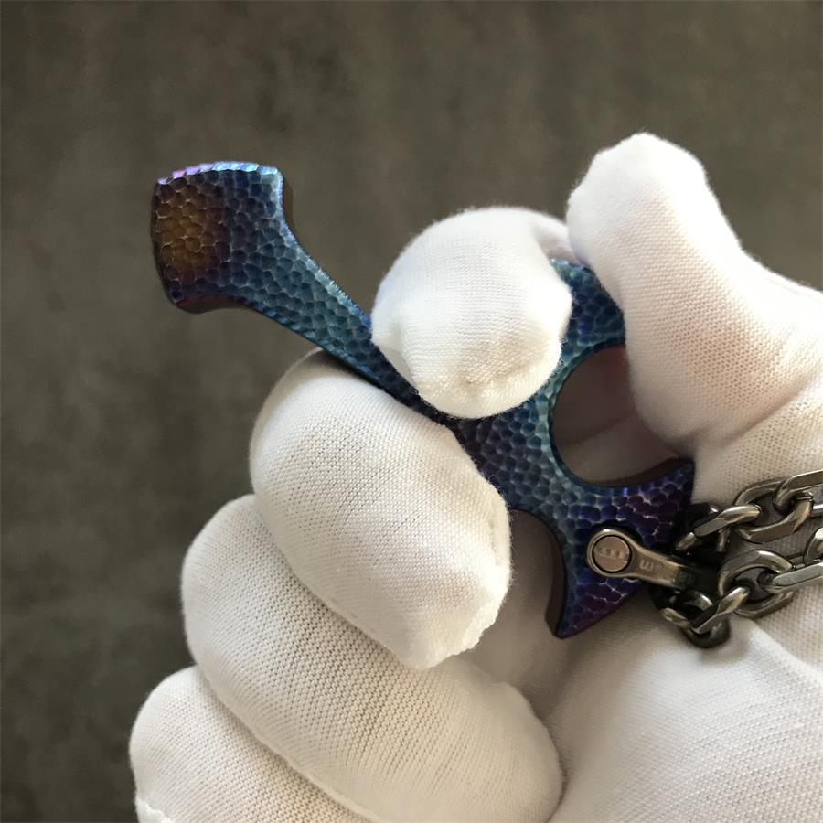 Close up angled view of Blaze titanium cross pendant showing shackle connection and hammered edge detail