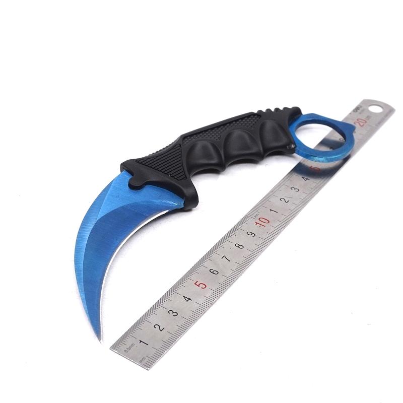 Single blue one-hole karambit knife displayed next to a metal ruler