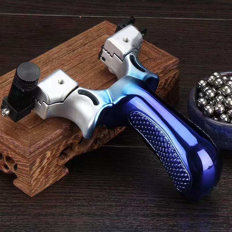 Blue slingshot with a silver fade resting on a carved wooden box, laser module mounted on one fork arm