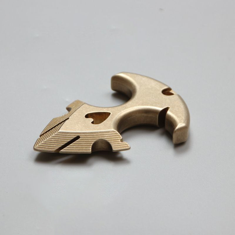 Close-up of the brass anchor pendant from a low angle, showing the stepped ridges on the flukes and the heart cutout.