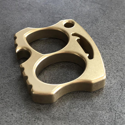Brass two-hole knuckle resting angled with scalloped bottom edge visible