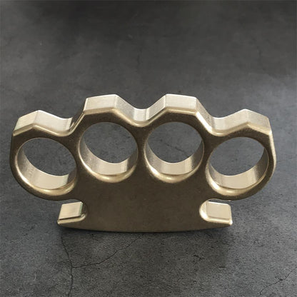 Front face of the stonewashed brass knuckle duster laid flat on a dark textured surface.