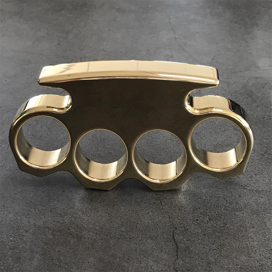 Front view of a mirror polished brass knuckle duster standing on a dark stone surface