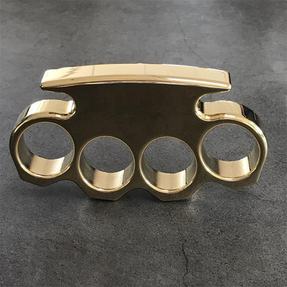 Front view of a mirror polished brass knuckle duster standing on a dark stone surface