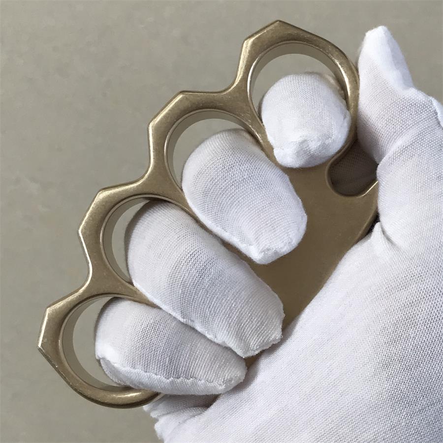 Gloved hand gripping the brass knuckle duster with fingers through the four rings.