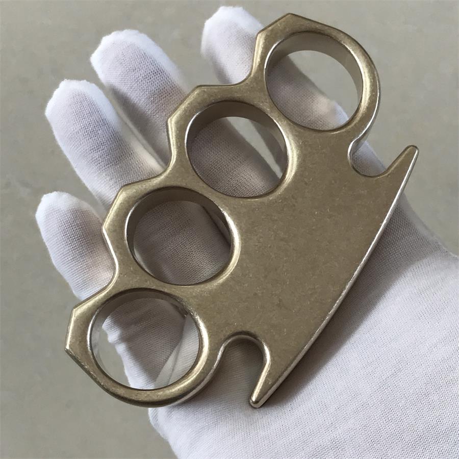 Handheld front view of the stonewashed brass knuckle duster against a neutral background.