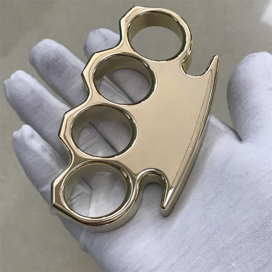 Brass knuckle duster laid across an open white gloved palm with the four finger holes facing up