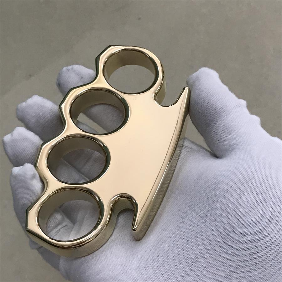 Brass knuckle duster resting on a white gloved palm with the classic frame and pointed ends in view