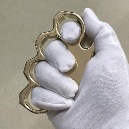Brass knuckle duster held upright in a white gloved hand with the pointed ends facing up and down