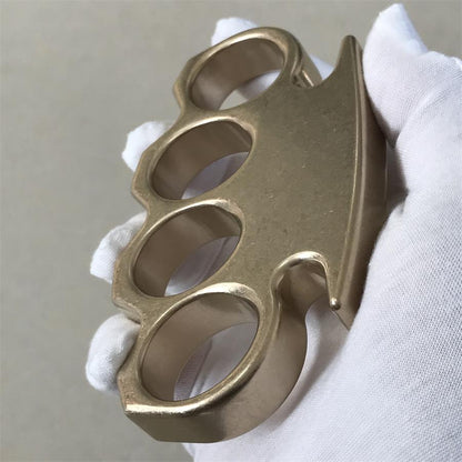 Tilted side view of the brass knuckle duster held in a gloved hand.