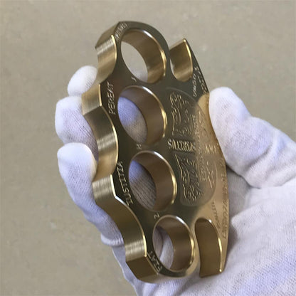 Brass knuckle duster worn across a white gloved hand with the fingers resting through the four holes