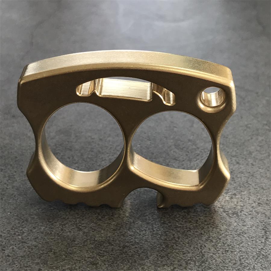 Brass knuckle standing on edge showing opener slot and lanyard hole