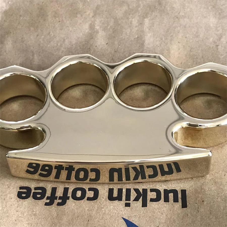 Closeup of the finger hole rims on a mirror polished brass knuckle duster resting on white fabric