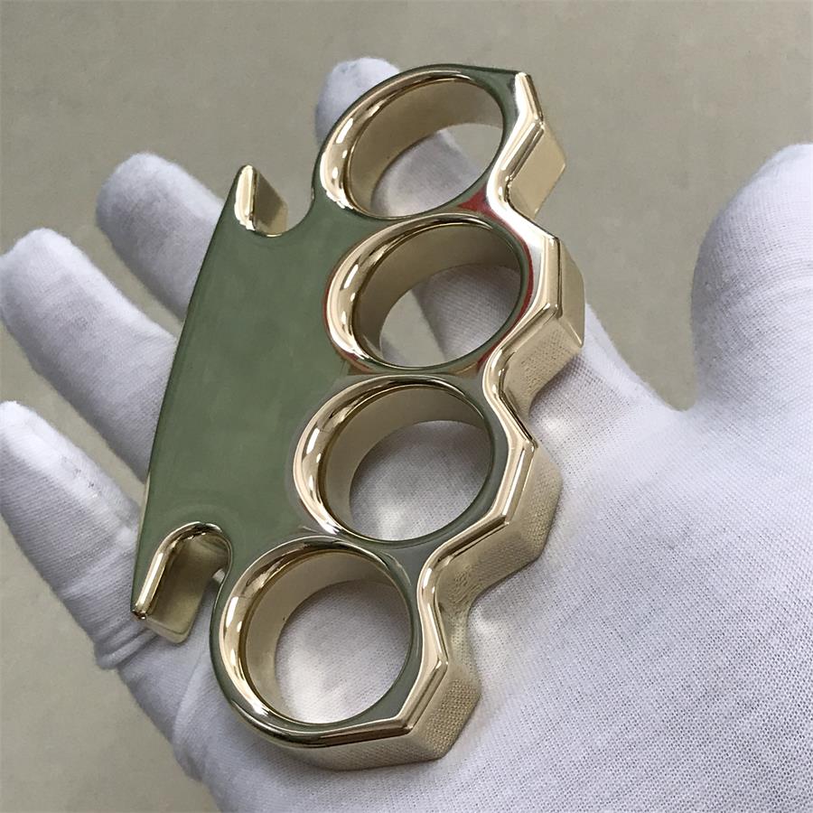 Mirror polished brass knuckle duster resting across a white gloved palm with the top bar to the left
