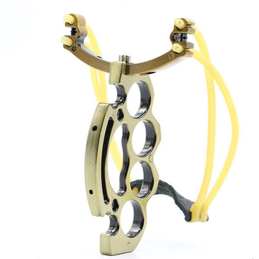 Brass-tone knuckle slingshot standing upright with yellow bands and leather pouch, four finger holes in the grip
