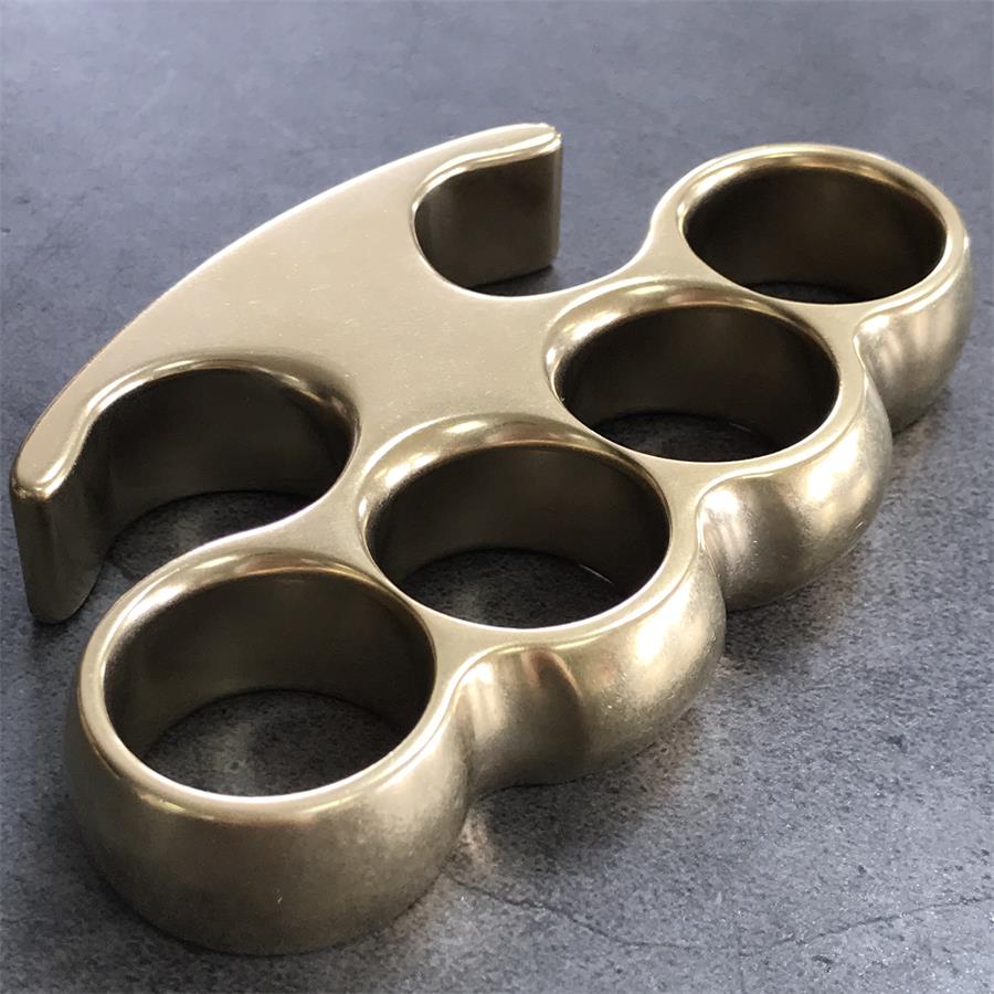 Brass knuckle duster viewed at an angle, stone-washed surface with a glossy polish