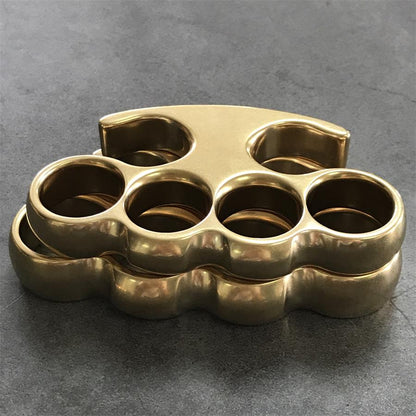 Two brass knuckle dusters stacked together, showing body thickness and the curved lower edge