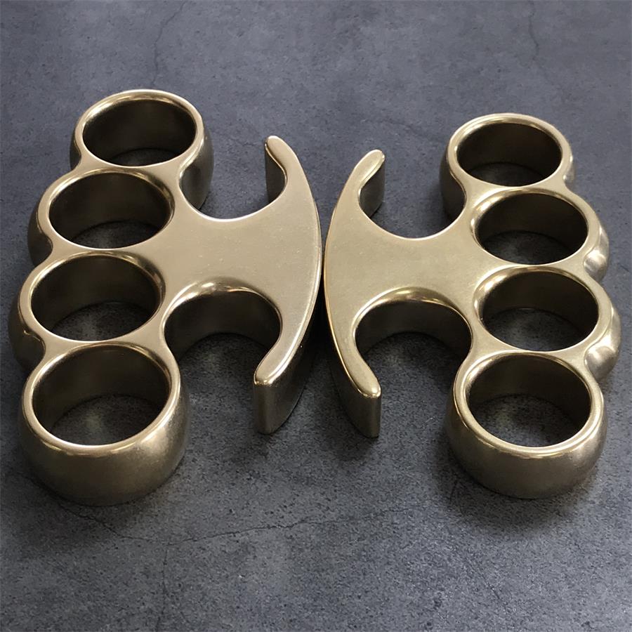 Large and Medium brass knuckle dusters standing upright side by side on gray concrete