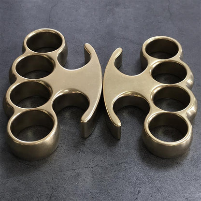 Large and Medium brass knuckle dusters standing upright side by side on gray concrete