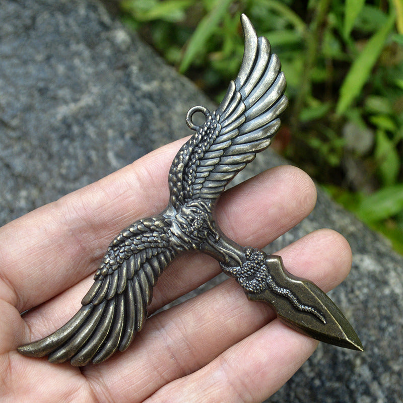 Bronze eagle pendant held across the palm showing the feather detail and hanging ring outdoors