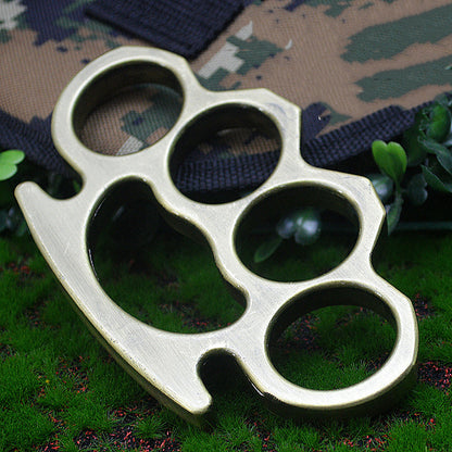 Bronze-H aluminum knuckle duster on camouflage fabric and grass close-up