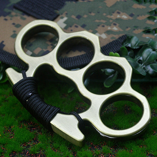 Bronze-H aluminum knuckle duster with black paracord on camouflage fabric and grass