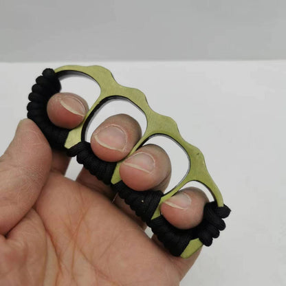 Bronze knuckle duster worn across four fingers, black paracord coils along the wavy upper edge