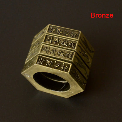 Bronze stacked hexagon ring standing upright showing engraved characters on every band against a dark background