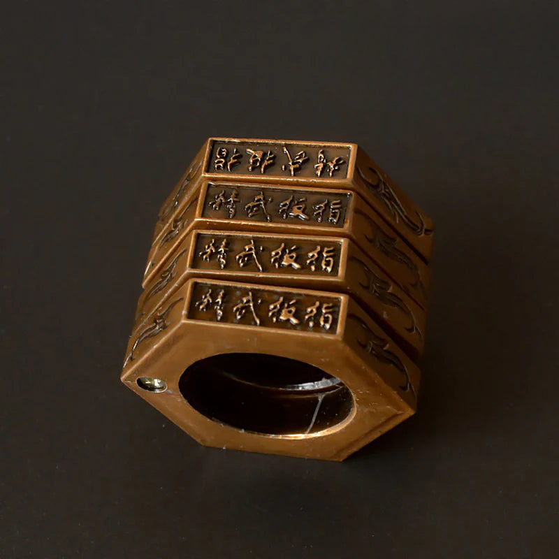 Bronze stacked hexagon ring standing upright on a dark background with a small screw stud at the band seam