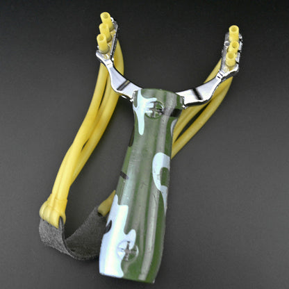 Camouflage water transfer slingshot with green patterned handle and yellow band strands on a dark grey background