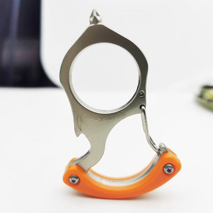 Orange handled carabiner keychain tool standing upright on a white table, pointed tip up, large round hole centered and Silver Knight engraving visible