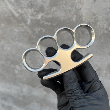 A black-gloved hand displays the 304 stainless steel classic knuckle duster facing forward.