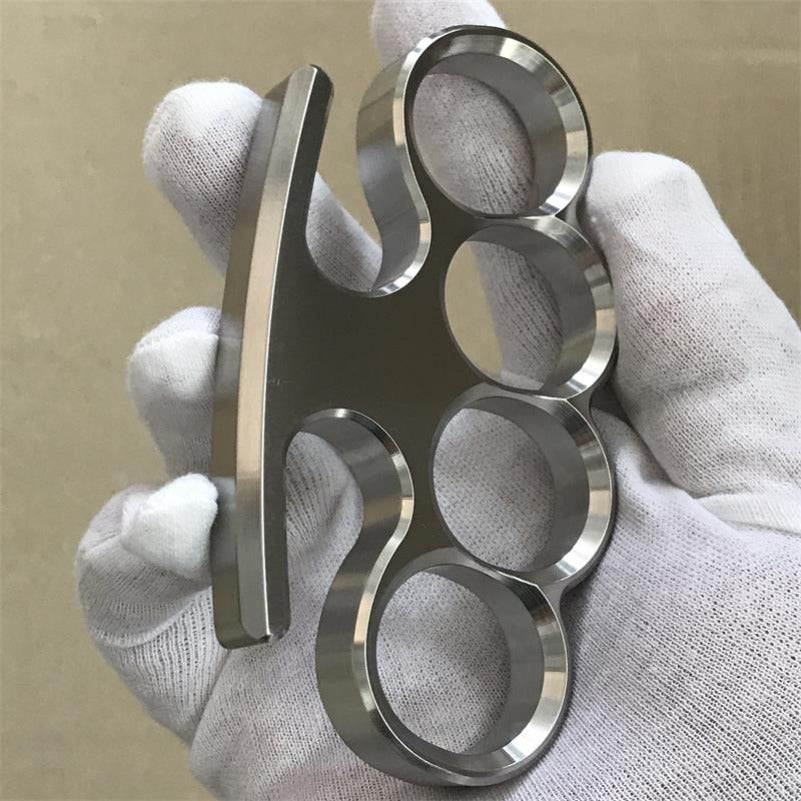 A gloved hand presents the 304 stainless steel classic knuckle duster at eye level.