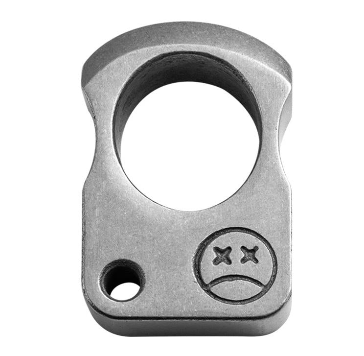 Dark single-hole knuckle weight held between fingers showing the faceted bevels and stone washed texture