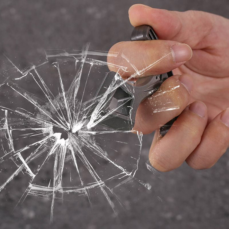 Hand holding the metal pendant against a shattered window, with cracks radiating from the point of impact.