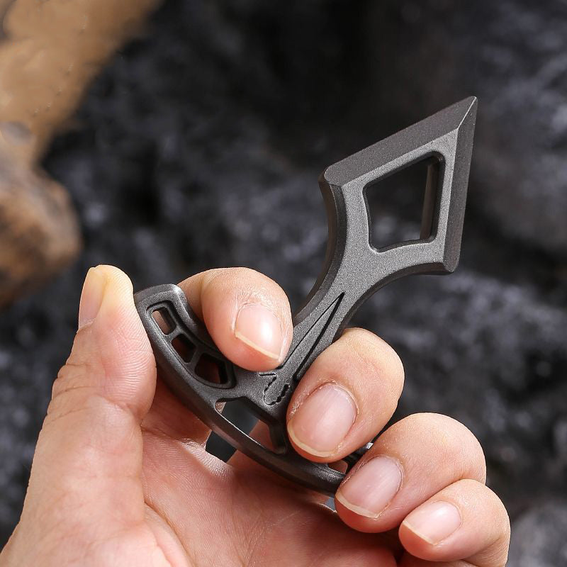 Hand holding the metal pendant by its slotted bar with the pointed tip facing up.