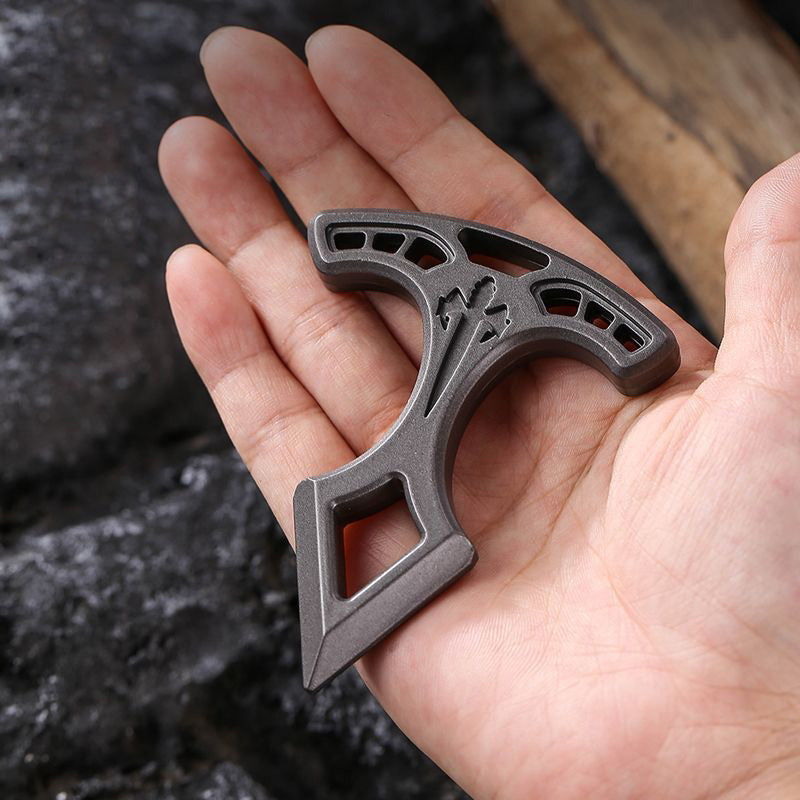 Metal pendant resting on an open palm for scale, showing the T-bar slots and the engraved cross on the face.