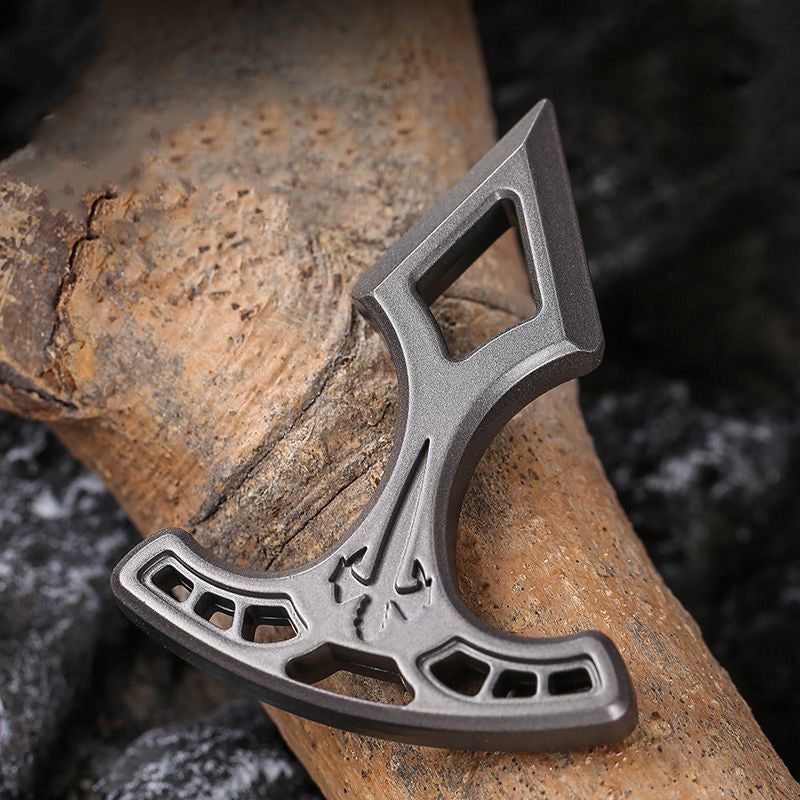 Metal pendant laid upside down on a log, showing the beveled edges and the diamond cutout near the tip.