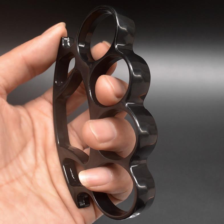 Black knuckle duster with window breaker held in hand showing side profile