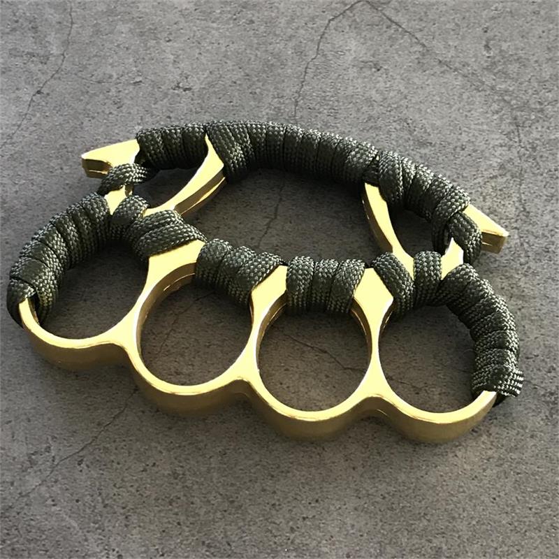 Gold and black knuckle dusters with paracord grips placed on stone surface