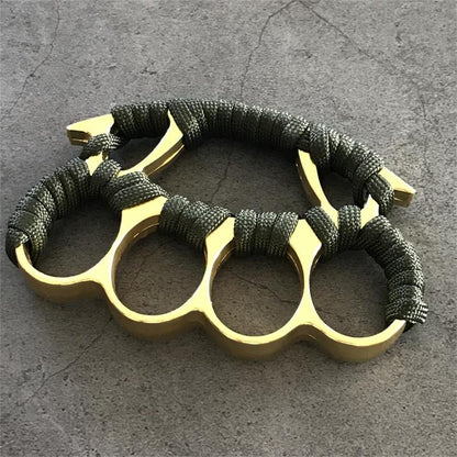 Gold and black knuckle dusters with paracord grips placed on stone surface