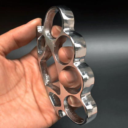Silver chrome knuckle duster with window breaker held in hand showing side profile