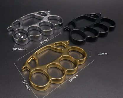 Three knuckle dusters in silver black and gold arranged with size measurements