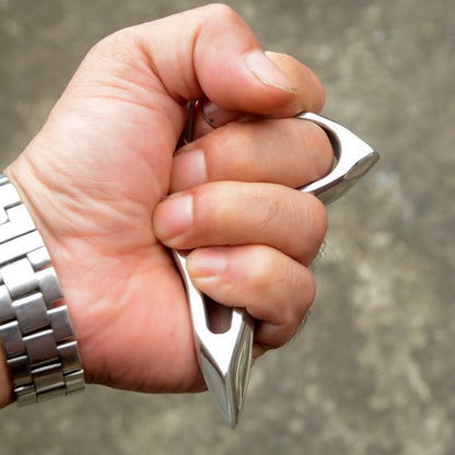 Closed-fist grip demonstration of the silver steel single-hole knuckle duster with the pointed tip facing forward