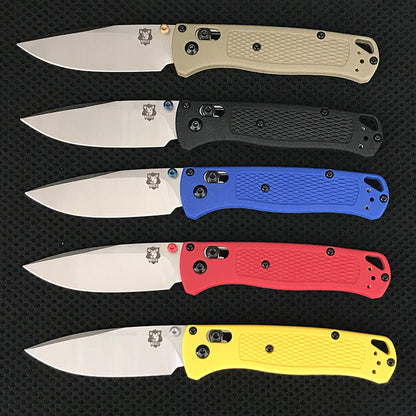 Five folding knives with satin silver drop-point blades and textured handles in tan, black, blue, red and yellow lined up in rows
