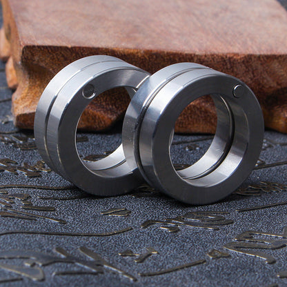 Two folded stainless steel cylinders standing on an engraved mat with a wooden block, groove lines and pivot screws visible