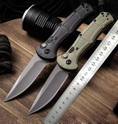 Two open folding knives beside a steel ruler on a wooden table