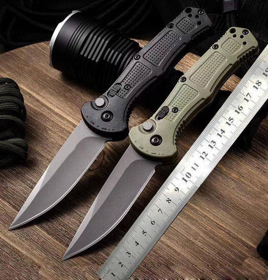 Two open folding knives beside a steel ruler on a wooden table