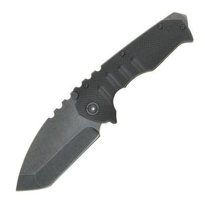 The open knife with a black textured G10 handle on white, showing finger grooves across the grip and a pivot with a brass-toned centre, above the stonewashed blade.