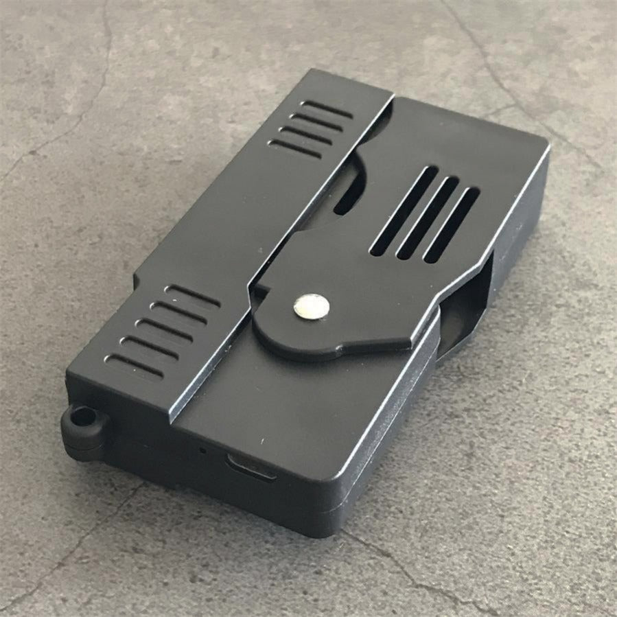 Folded stun gun on concrete showing the flat profile with a small port on the lower edge and a lanyard hole